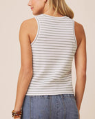 Woman wearing a striped tank top and jeans on a beige background