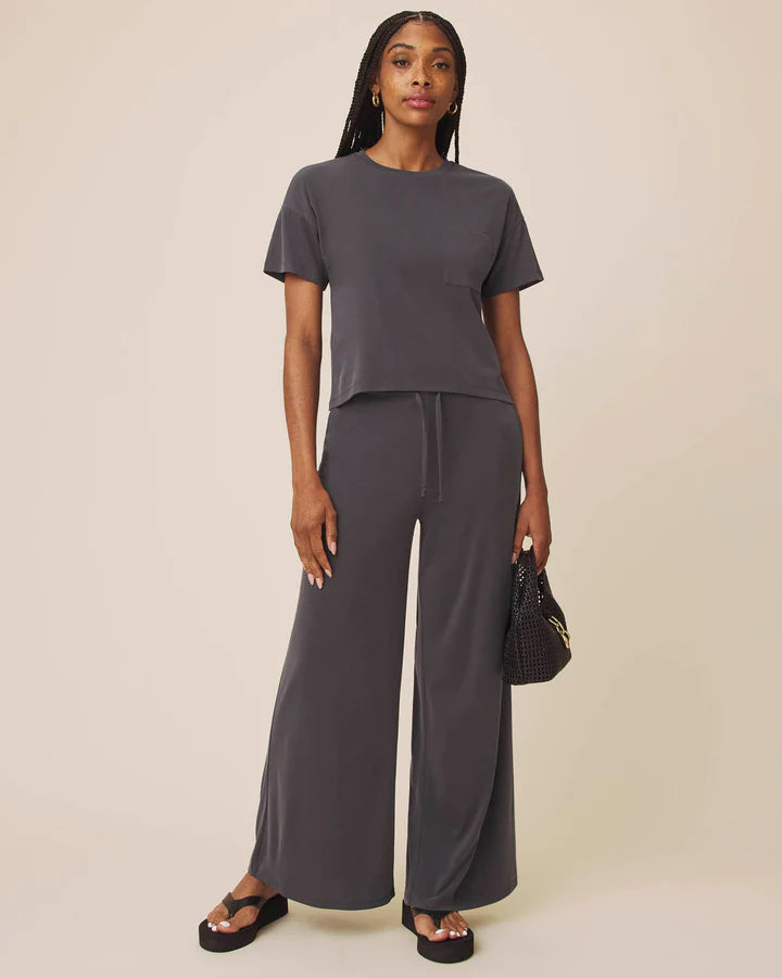 Woman wearing a gray outfit with wide-leg pants on a beige background