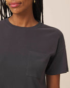Black t-shirt with a pocket worn by a person on a neutral background