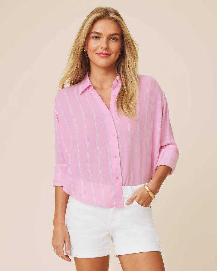 Woman wearing a pink blouse and white shorts against a beige background