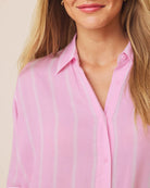 Close-up of a person wearing a pink striped shirt with a neutral background