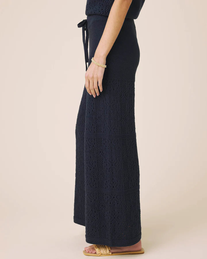 Navy blue knitted pants worn by a person on a beige background