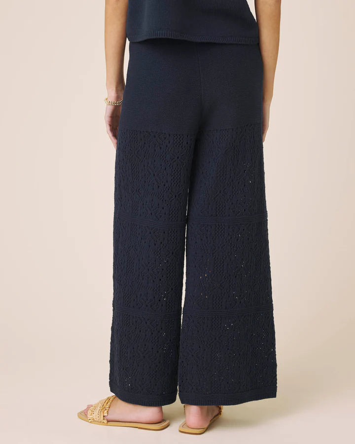 Navy blue textured wide-leg pants worn by a person on a beige background