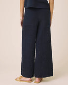 Navy blue textured wide-leg pants worn by a person on a beige background