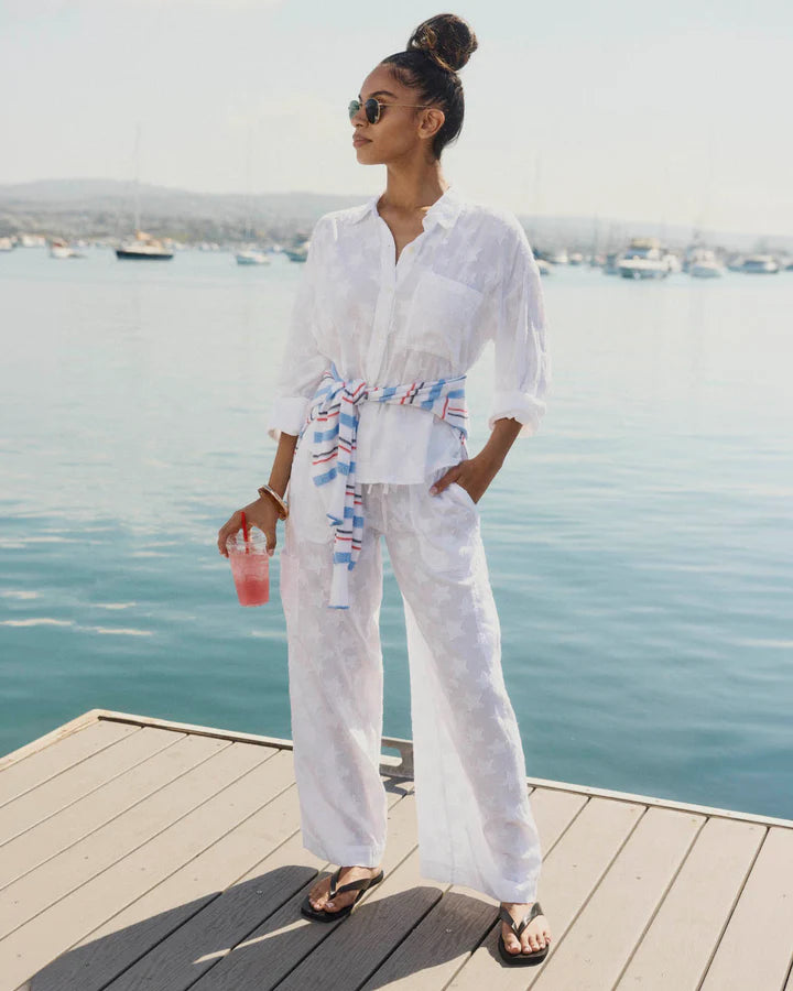 Woman in white outfit standing on a dock by the water