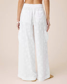 White wide-leg pants worn by a person on a beige background