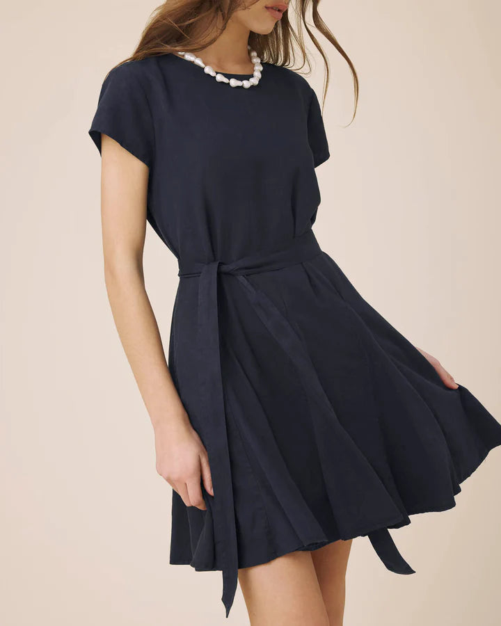 Navy blue dress with a tie waist worn by a person on a beige background