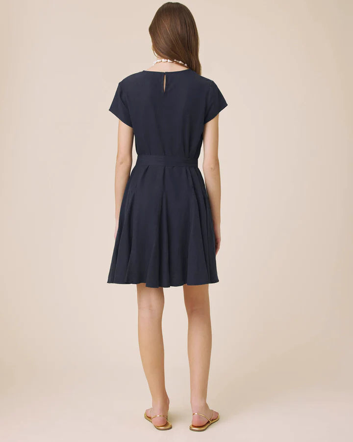 Woman wearing a navy blue dress against a beige background