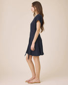Woman wearing a navy blue dress against a beige background