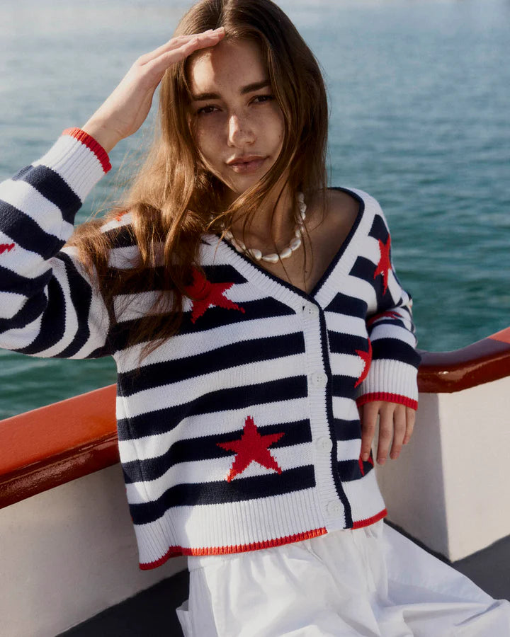 Woman wearing a nautical-themed sweater with red stars on a boat.