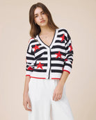 Woman wearing a black and white striped cardigan with red stars on a beige background