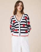 Woman wearing a black and white striped cardigan with red star patterns on a beige background