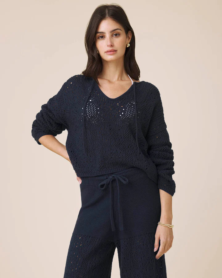 Woman wearing a navy blue knit outfit on a beige background