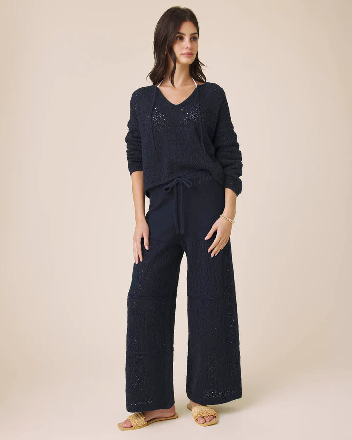 Woman wearing a navy blue outfit with wide-leg pants on a beige background
