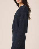 Navy blue knitted cardigan worn by a person on a beige background