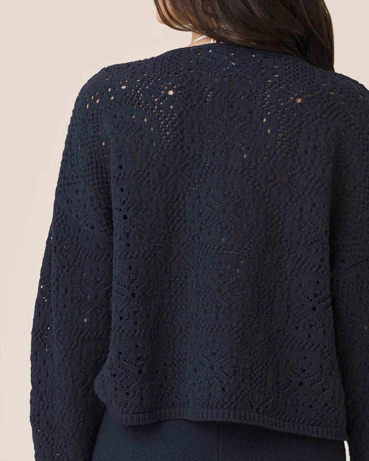 Navy blue textured cardigan worn by a person on a beige background
