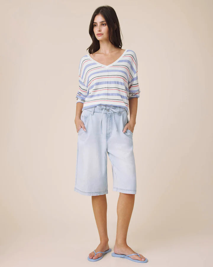 Woman wearing a striped top and light blue shorts on a beige background