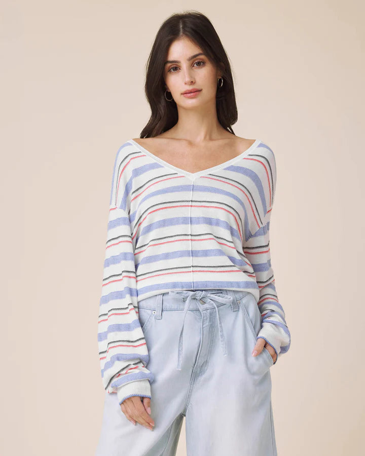 Woman wearing a striped sweater and light pants against a beige background