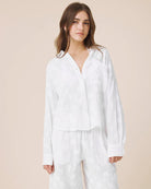 Woman wearing a white outfit against a beige background