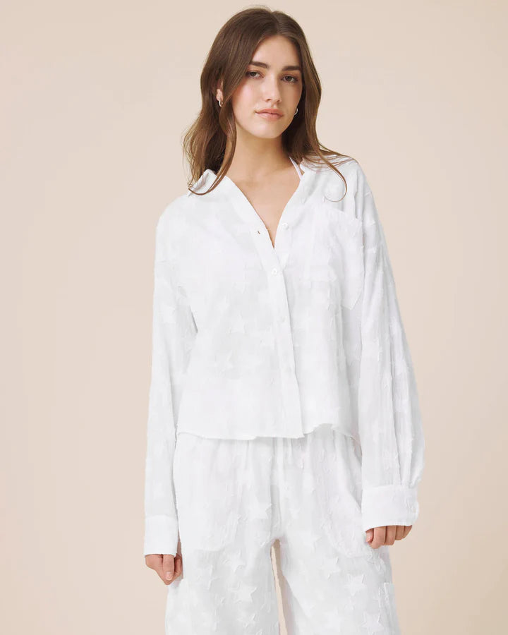 Woman wearing a white outfit against a beige background