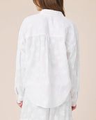 Person wearing a white shirt against a beige background