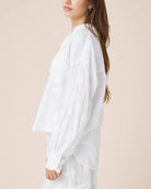 Woman wearing a white outfit against a beige background