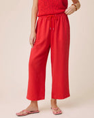 Person wearing red pants and a red top on a beige background