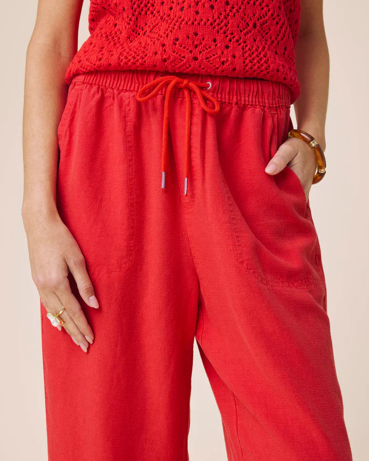 Person wearing a red crochet top and red pants on a beige background