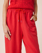 Person wearing a red crochet top and red pants on a beige background