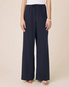 Navy wide-leg pants worn by a person on a beige background