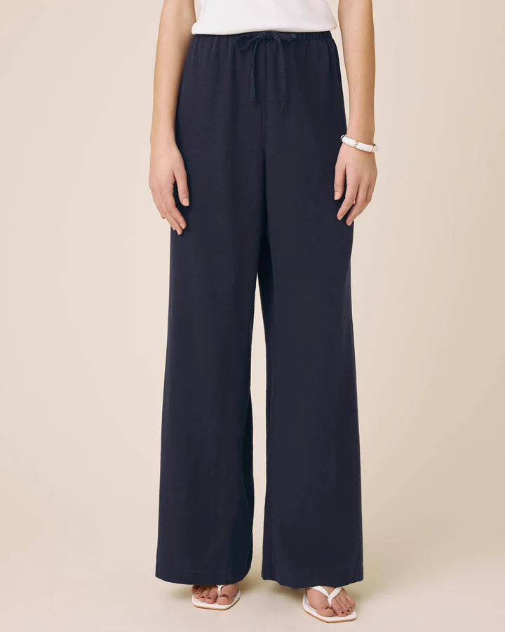 Navy wide-leg pants worn by a person on a beige background