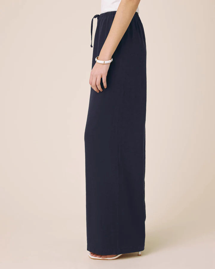 Navy blue wide-leg pants worn by a person on a beige background