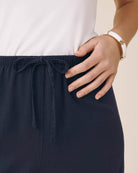 Navy blue pants with a white shirt and beige background