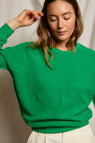 Woman wearing a green sweater against a neutral background