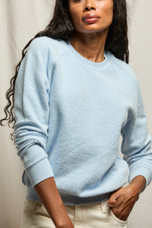 Woman wearing a light blue sweater against a neutral background
