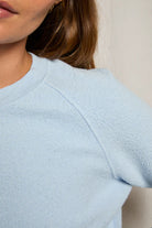 Light blue textured sweater worn by a person with a neutral background