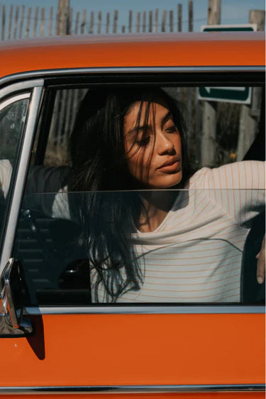 Woman sitting inside an orange vehicle with a blurred background