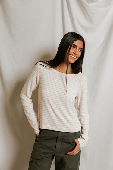 Woman wearing a white striped sweater and green pants against a plain background