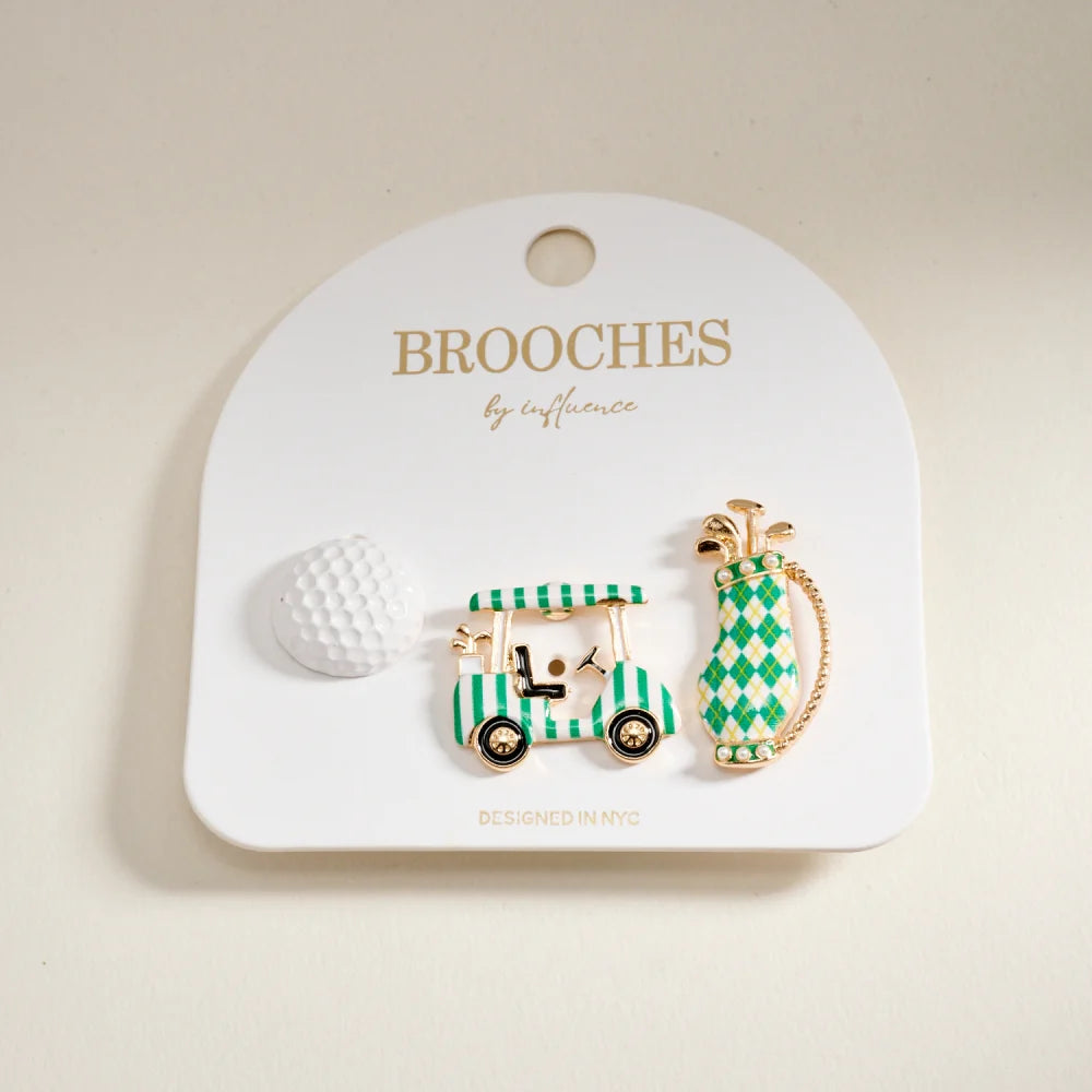 Two decorative brooches on a 'Brooches by Influence' card against a beige background.