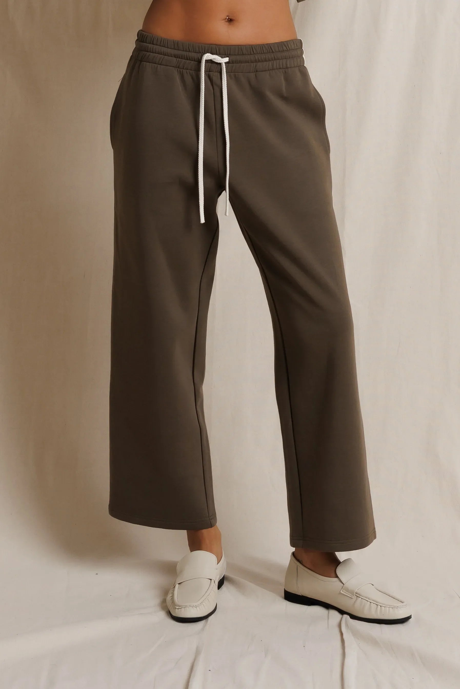 Brown pants with a white drawstring on a neutral background