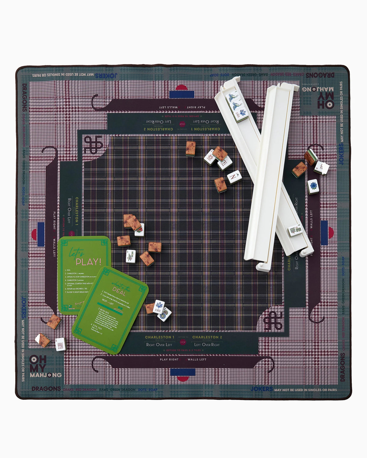 A board game set laid out flat on a white background, featuring a large plaid game board, two white plastic dice cups, several small brown tokens, and two green cards. The board has visible text including 'SNOOZE', 'ON + PIVER', and 'MAMLO NO'.