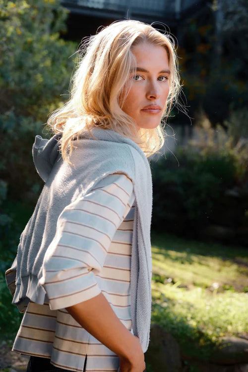 Woman wearing a striped shirt and gray cardigan in a garden setting