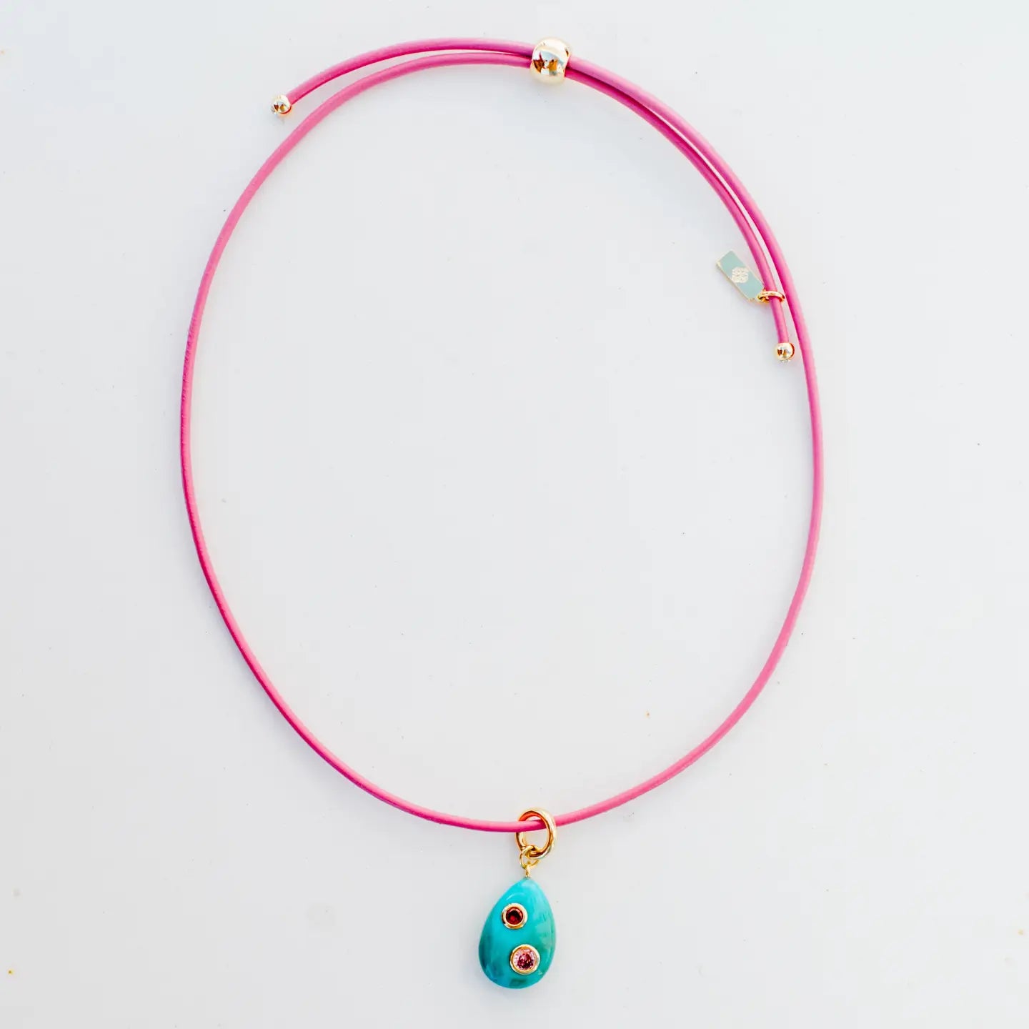 Pink necklace with a turquoise pendant on a light gray background