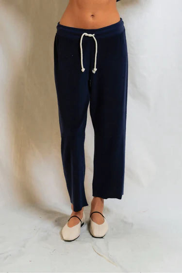 Navy blue jogger pants with a white drawstring on a light background