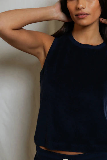 Woman wearing a dark blue sleeveless top against a neutral background