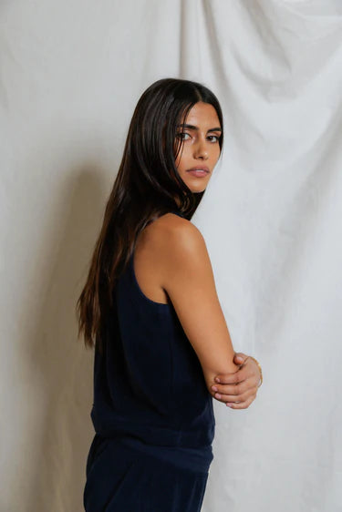 Woman wearing a dark blue sleeveless top against a plain white background