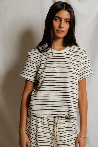 Woman wearing a black and white striped t-shirt and pants against a plain background