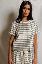 Woman wearing a black and white striped t-shirt and pants against a plain background