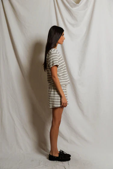 Person wearing a striped outfit standing against a plain white background