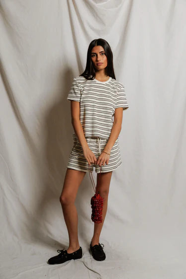 Woman wearing a striped outfit holding a red and black object against a plain background
